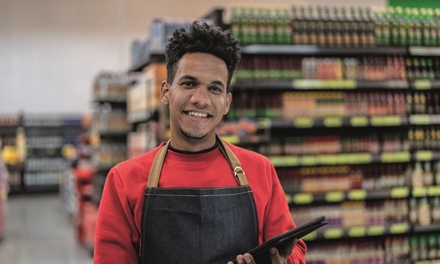 Student Retail medewerker is aan het werk in de supermarkt en lacht in de camera